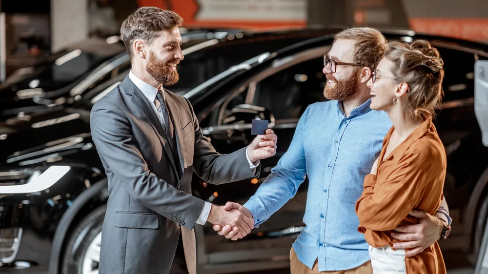 Verkausberatung mit 2 glücklichen Kunden im Autohaus